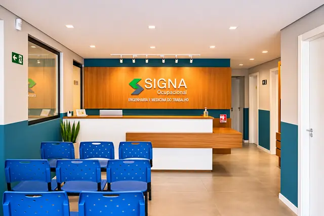 Recepção da Signa Ocupacional com painel em madeira, logotipo e cadeiras de espera azuis